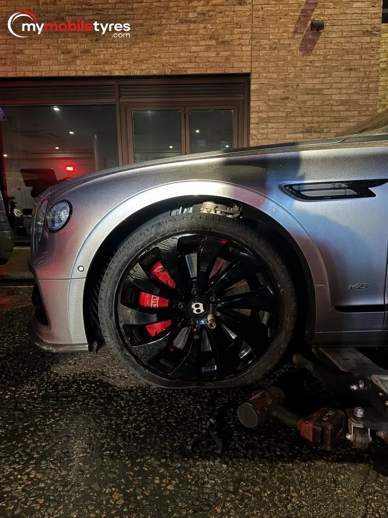 Mobile tyre fitter replacing a flat tyre at the roadside in Westminster